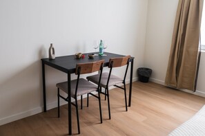 En liten matplats med ett bord, stolar, en vas, en flaska och ett glas.
