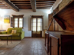 A rustic interior with a green sofa, wooden cabinets, and a tiled floor. - "Poggio del Pero" by Interhome (Panicale)