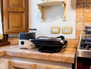 A kitchen with a countertop, a stove, a wall-mounted electrical outlet, and a cabinet. - "Poggio del Pero" by Interhome (Panicale)