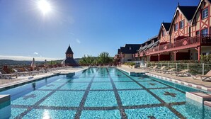 En swimmingpool med ett mönstrat kakel, solstolar och en byggnad med en balkong.