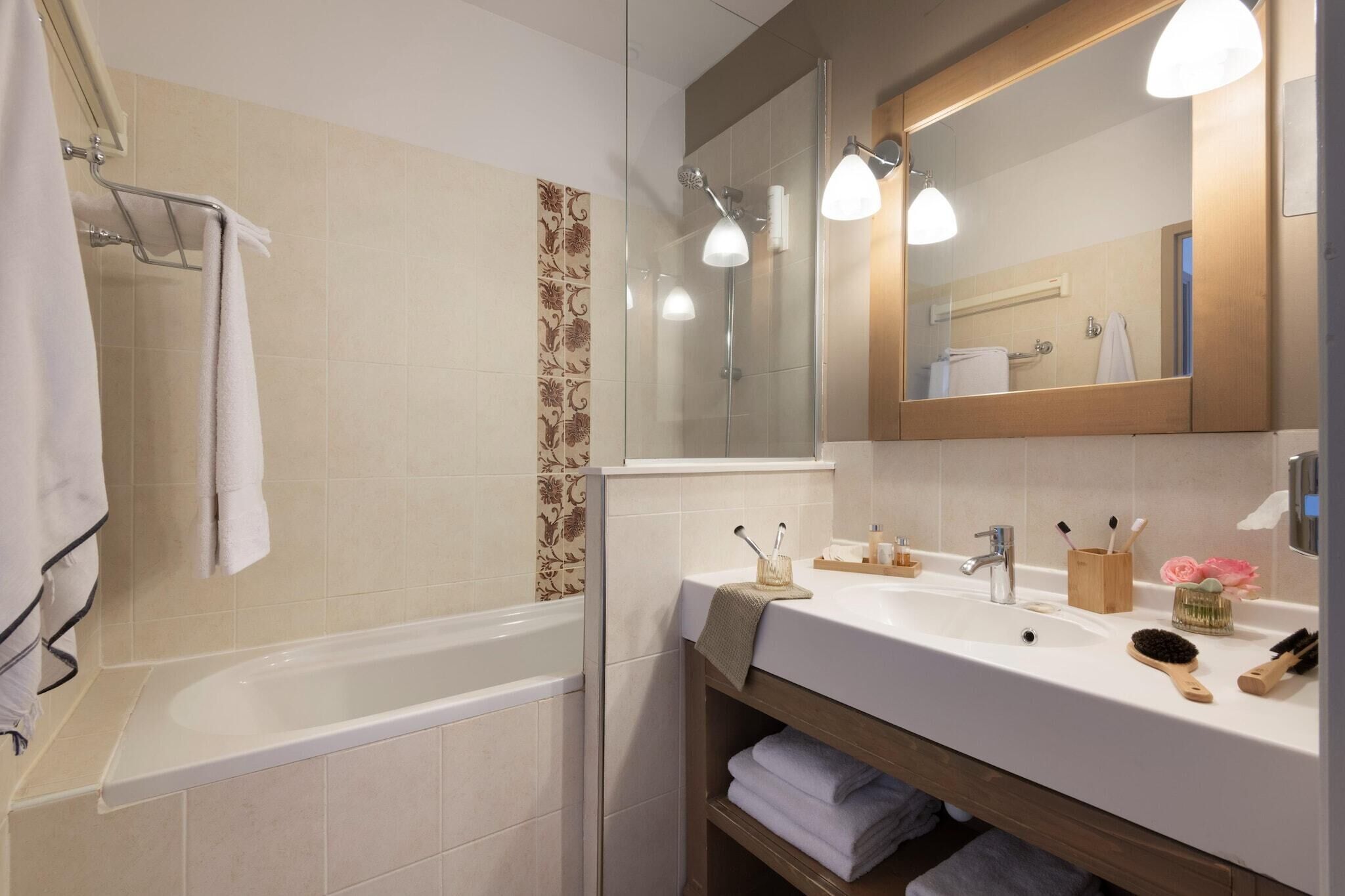 Une salle de bain moderne avec une baignoire, un lavabo avec un miroir et un espace douche.