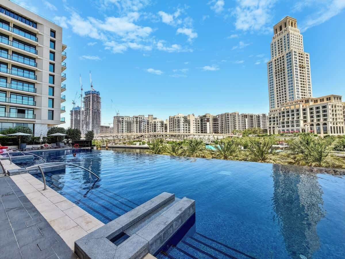 A pool with a cityscape view, modern buildings, and a clear sky.