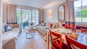 Un salon comprenant un canapé, une table à manger, des chaises et offrant une vue dégagée grâce à de grandes fenêtres.