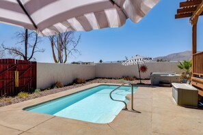 A swimming pool with a metal ladder, a wooden deck, and a covered seating area with an umbrella. - Home w/ Outdoor Oasis & Views in Borrego Springs! (Borrego Springs)
