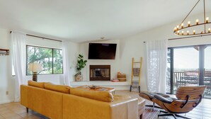 A living room with a sofa, a chair, a flat-screen TV, a fireplace, and a balcony. - Home w/ Outdoor Oasis & Views in Borrego Springs! (Borrego Springs)
