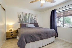A bedroom with a bed, a nightstand, a ceiling fan, a window with curtains, and a wall-mounted artwork. - Home w/ Outdoor Oasis & Views in Borrego Springs! (Borrego Springs)