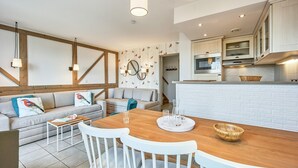 Een moderne keuken met witte kasten, een houten eettafel en een inbouwoven.