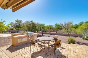 Eine Terrasse im Freien mit Grill, Sitzgelegenheiten und Blick auf die umliegende Landschaft.