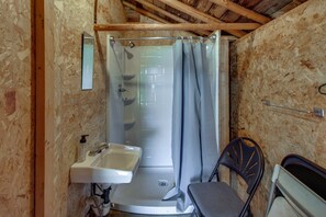 Ducha con puerta de cristal, lavabo y silla.