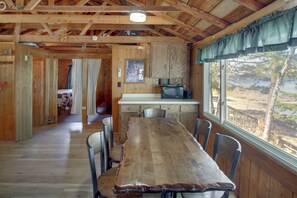 Interior de madera con una mesa de comedor, sillas, microondas y ventana con vistas.