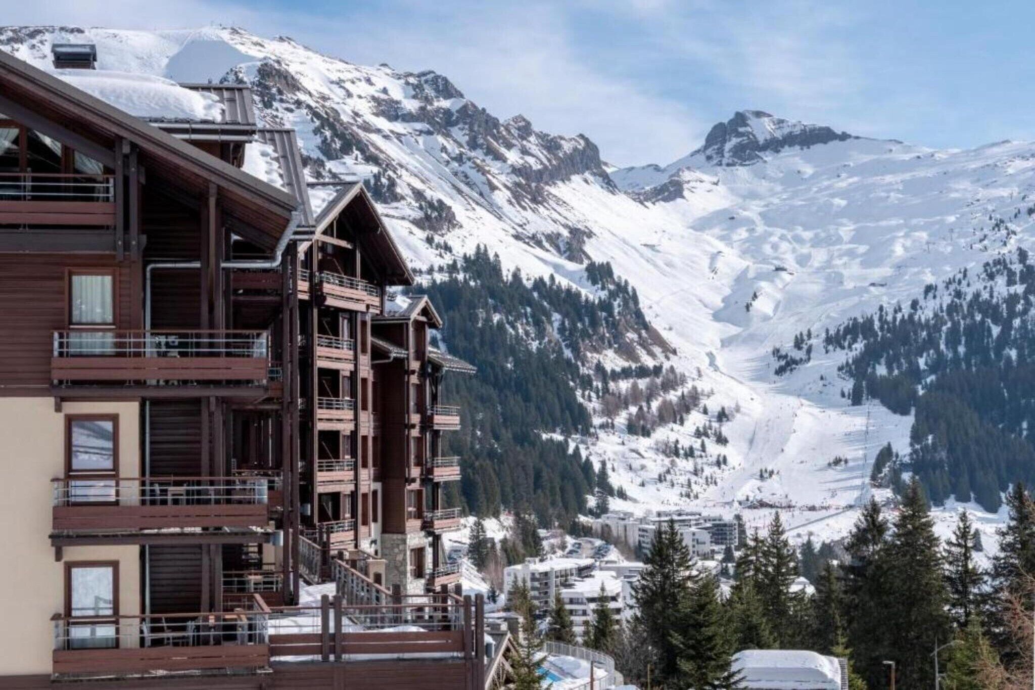 Ein mehrstöckiges Hotel mit Balkonen mit Blick auf eine verschneite Berglandschaft.