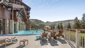 Ett poolområde med solstolar och utsikt över bergen.
