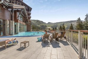 A pool area with lounge chairs and a view of mountains. - Alps Flat with Heated Pool (Flaine)