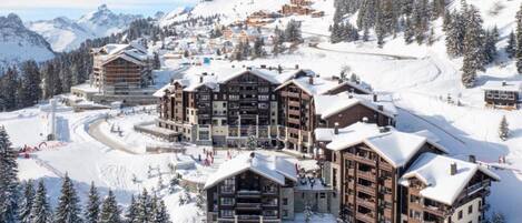 Ein Skigebiet mit mehreren Chalet-ähnlichen Gebäuden, Skipfällen und schneebedeckten Bäumen.