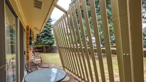Eine Terrasse mit Tisch und Stühlen, ein Holzzaun und Blick auf einen Garten mit Bäumen.