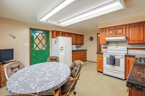 Eine Küche mit Holzausstattung, einem weißen Kühlschrank, einem Herd und einem Esstisch mit Stühlen.