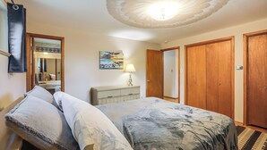 Ein Schlafzimmer mit einem Bett, einem Schminktisch, einem Spiegel und Holztüren.