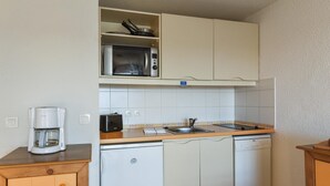 Kompakti keittiö, jossa on mikroaaltouuni, kahvinkeitin, pesuallas ja astianpesukone.