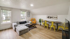 Una sala de estar con sofá, reposapiés, mesa de centro y sillas amarillas.