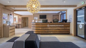 Una recepción con diseño de madera y un logotipo, un área de espera con asientos acolchados y una gran lámpara decorativa.