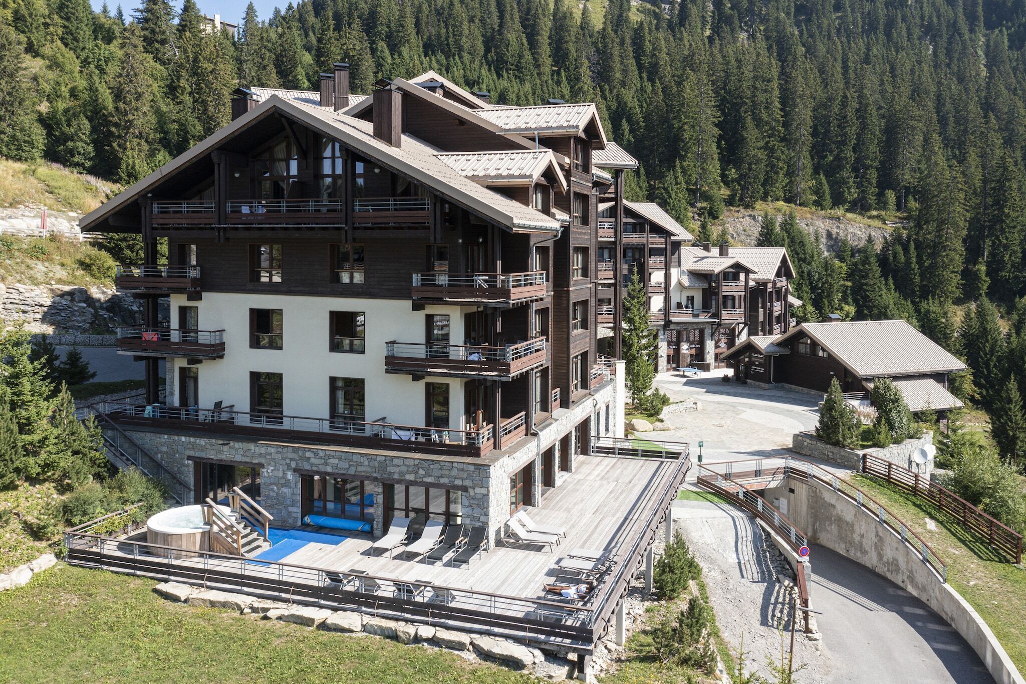 A multi-story mountain lodge with balconies, a swimming pool, and a ski lift.