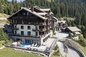 Ein mehrstöckiges Berglodge mit Balkonen, einem Schwimmbad und einer Seilbahn.