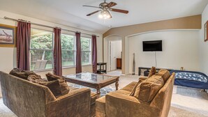 A living room with a sofa, armchairs, a coffee table, a ceiling fan, and a TV. - Fenced Yard & Patio! Family Escape in DFW Suburbs (Fort Worth)