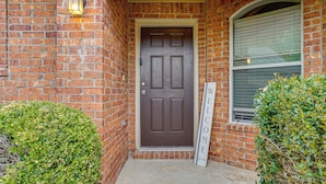 A brick building with a brown door, a welcome sign, and a window with blinds. - Fenced Yard & Patio! Family Escape in DFW Suburbs (Fort Worth)