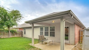 A single-story house with a covered patio, a lawn, and a wooden fence. - Fenced Yard & Patio! Family Escape in DFW Suburbs (Fort Worth)
