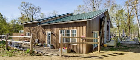 A wooden building with a green roof, a fenced area, and outdoor seating.