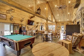 Interior de madera con mesa de billar, zona de comedor y varios trofeos de animales.