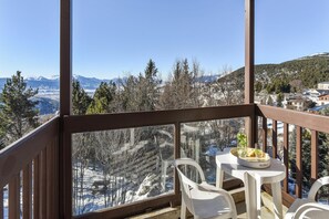 Ein Balkon mit Tisch und Stühlen mit Blick auf eine verschneite Berglandschaft.