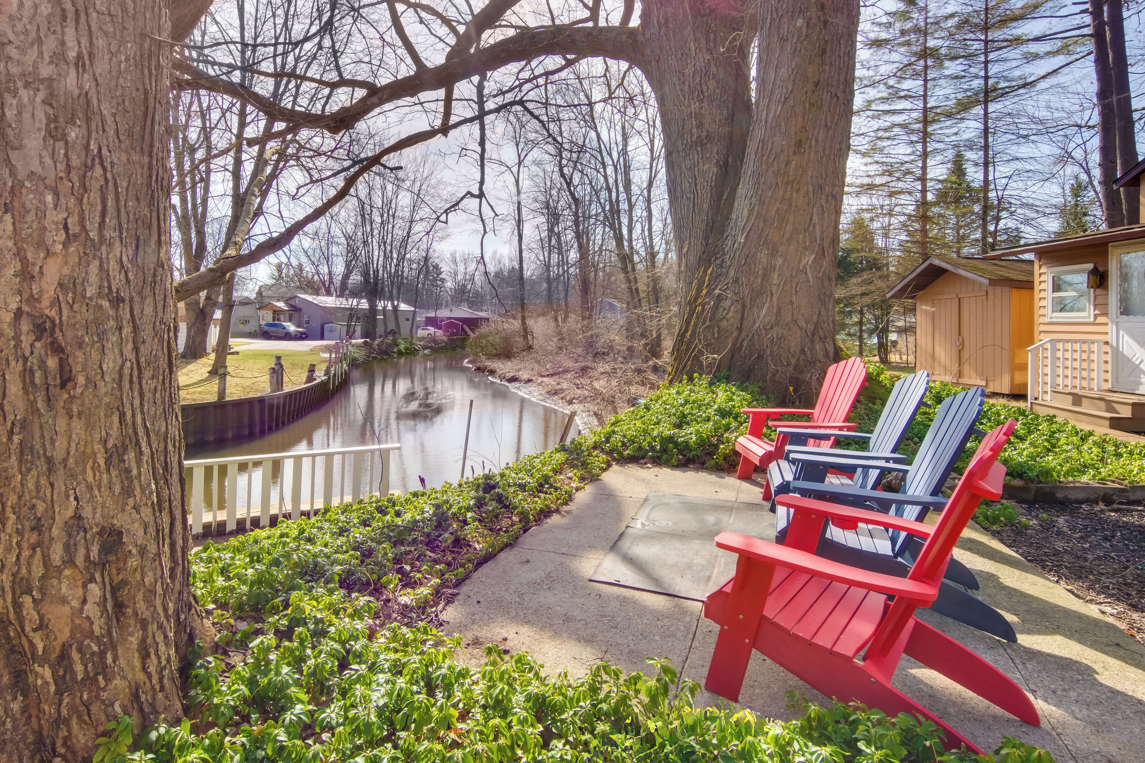 Une vue sur la rivière, avec des fauteuils Adirondack, un chalet en bois et un petit quai.