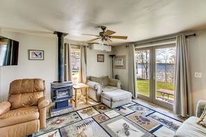 A living room with a sofa, a chair, a table, a ceiling fan, and a view of a deck.