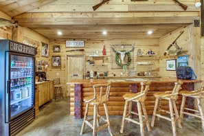 A rustic bar area with wooden furniture, a refrigerator, and a sign indicating a grocery section.