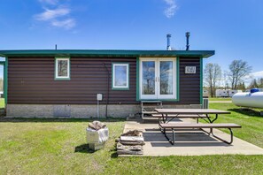 A small cabin with a picnic table and a covered woodpile.