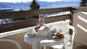A table with a teapot, cups, and pastries on a balcony with a mountain view. - Stunning Pyrenees Apartment for 4 (Font Romeu Ermitage)