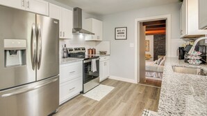 A modern kitchen with stainless steel appliances, white cabinetry, and a granite countertop. - 2 Mi to OKC Fairgrounds: Pet-Friendly Home w/ Yard (Oklahoma City)