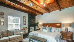 A bedroom with a bed, a bench, a nightstand, a dresser, a window, and a fireplace. - 2 Mi to OKC Fairgrounds: Pet-Friendly Home w/ Yard (Oklahoma City)
