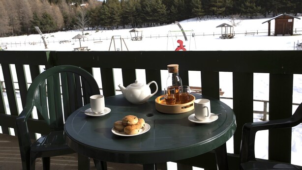 A table with a teapot, cups, and biscuits on a deck with a view of a snowy landscape. - Charming Pyrenees Mountain Getaway (Bolquere Pyrénées 2000)