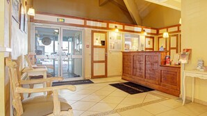 A reception area with a wooden reception desk, a waiting area with chairs, and a tiled floor. - Charming Pyrenees Mountain Getaway (Bolquere Pyrénées 2000)