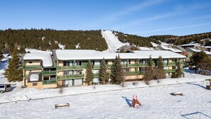 A hotel with multiple floors, a ski slope in the background, and a snow-covered ground. - Charming Pyrenees Mountain Getaway (Bolquere Pyrénées 2000)