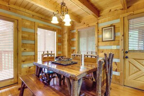 Ein Esszimmer aus Holz mit einem großen Tisch, Stühlen und einer Chandelüster.