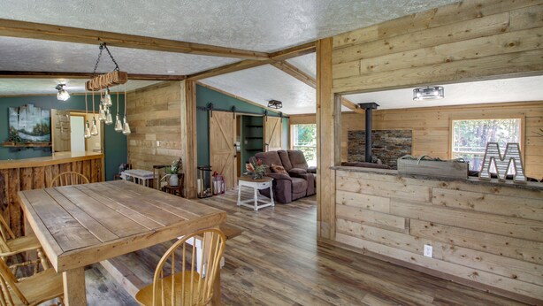 A rustic cabin interior with a wooden dining table, chairs, a sofa, and a fireplace. - Birch Haven Resort Cabin w/ Deck: Boating On-Site (Tenstrike)