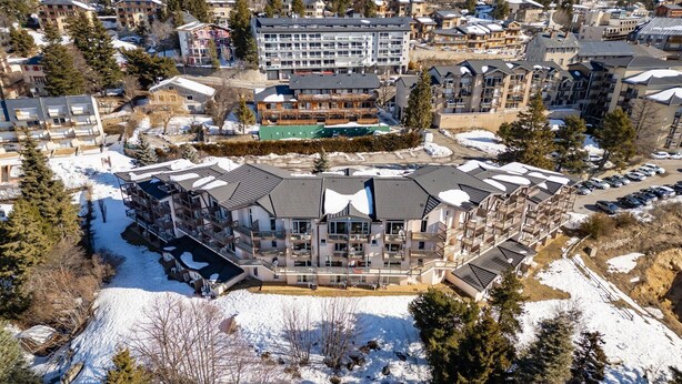 Un hotel de varios pisos con un patio central, rodeado de nieve en el suelo y árboles.