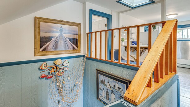 Eine Treppe mit einer Holzhandläufe, ein gerahmtes Bild einer Brücke und eine maritime Dekoration an der Wand.