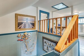 Un escalier avec une rampe en bois, un tableau encadré représentant un pont et une décoration sur le thème de la marine sur le mur.