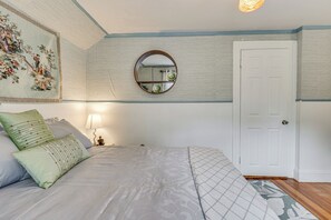 Un dormitorio con cama, espejo, puerta y pared decorada con una pintura floral.