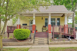 A two-story house with a porch, steps, and a small table with chairs.