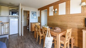 Eine kleine Küche mit Mikrowelle, Kühlschrank und einem Holztisch mit Stühlen.